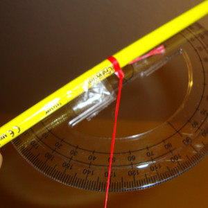 Experiment 27, Bild 4: Den Breitengrad bestimmen mit Winkelmesser, Schnur, Bleistift, Tesafilm, Schraube und Polarstern. Die Stelle, wo die Schnur die Skala schneidet, soll den Breitengrad in Grad angeben.